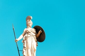 Eine Statue von Athene unter einem strahlend blauen Himmel. Sie ist Schutzgöttin der Stadt Athen, des Handwerks und der Künste, aber auch eine kriegerische Göttin.