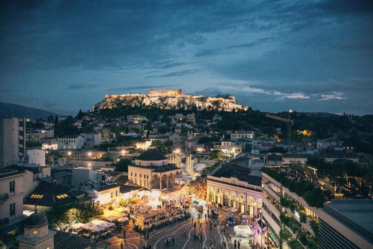 Blick über den belebten Monastiraki Platz auf die Akropolis in der Dämmerung von einer Roof-Top Bar in Athen